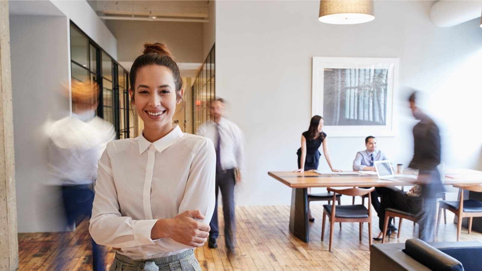 trade-credit-and-accounts-receivable woman in business casual smiling at camera with blurry individuals working in the background