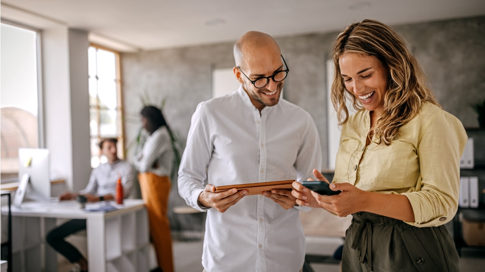 Man and woman coworkers looking at benchmark data on devices.