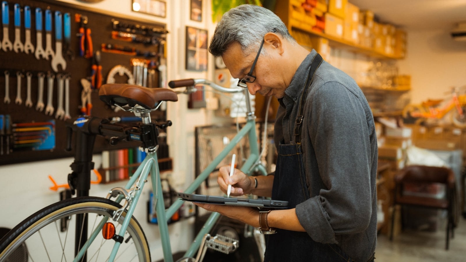 Asian male business owner reading on iPad.