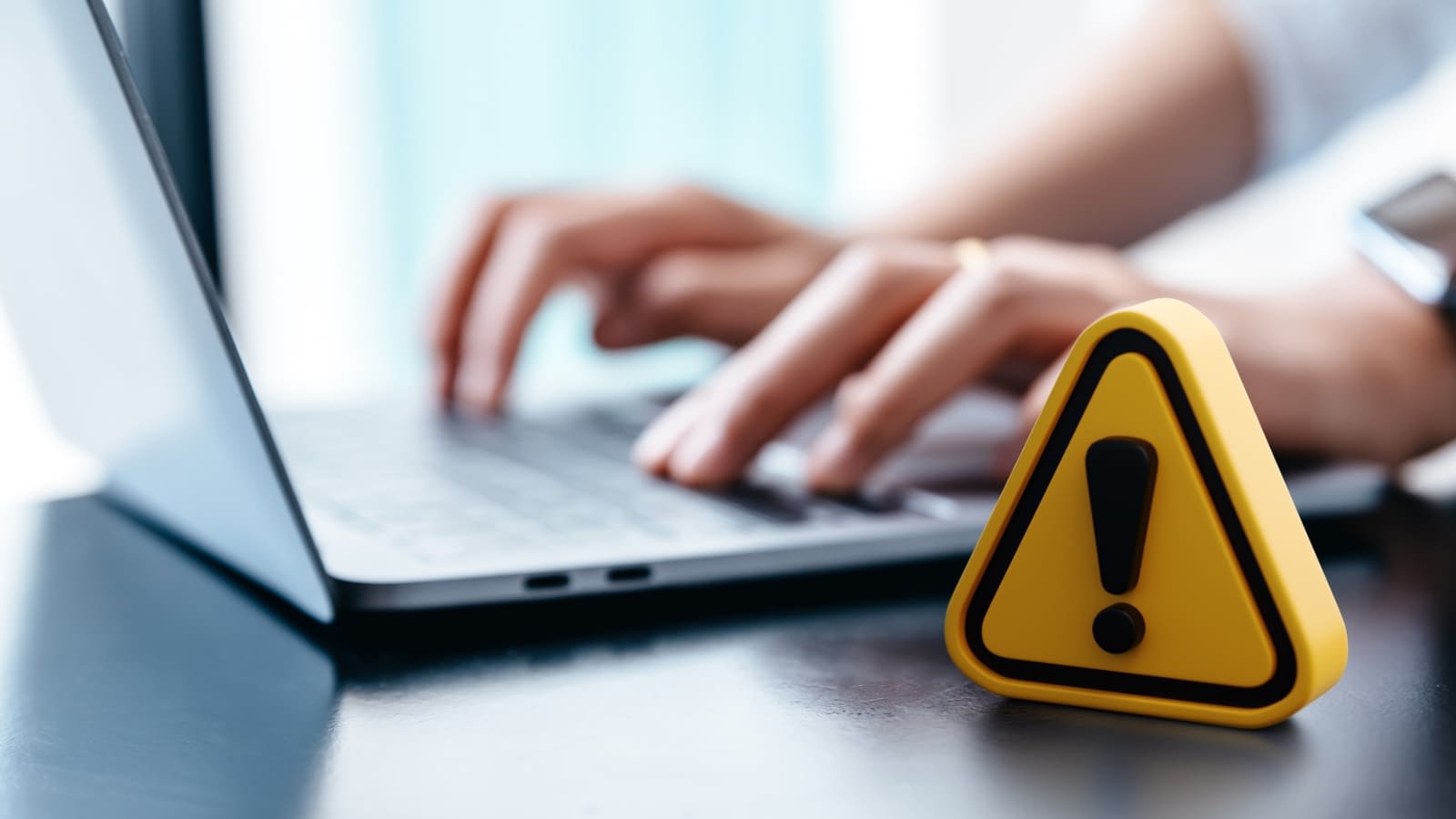 social media risks caution symbol in front of person working on computer