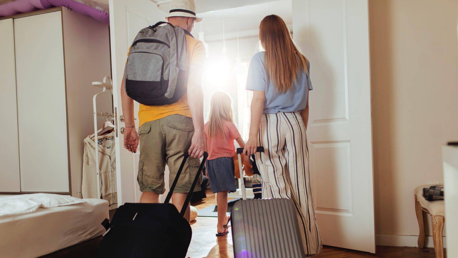 family of three leaving the house with luggage