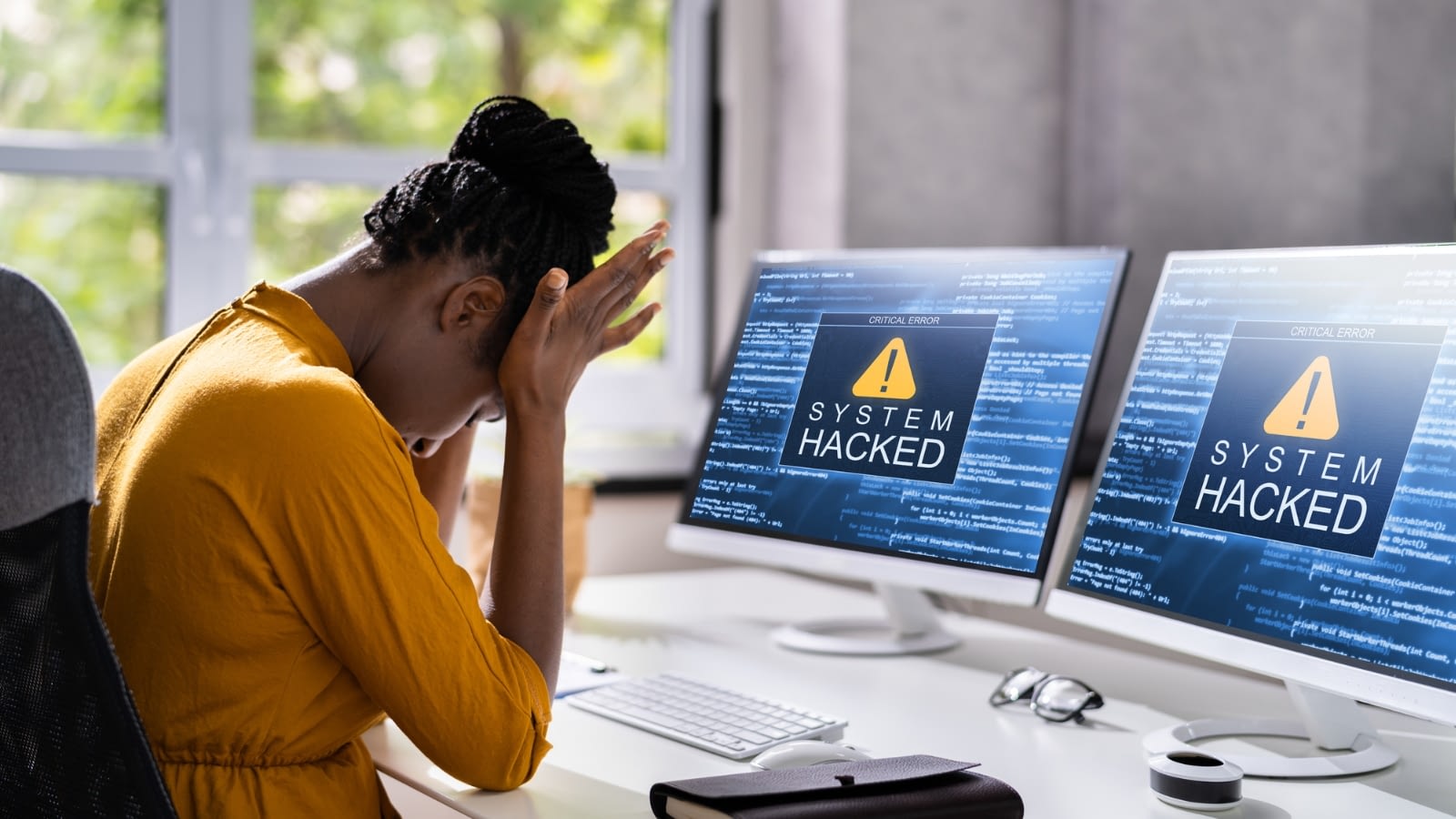 frustrated woman with two computers that have been hacked