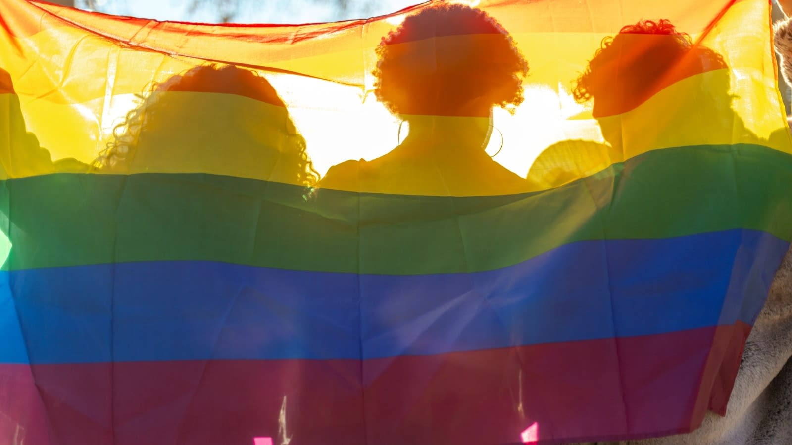 June 1 blog People standing behind a rainbow flag