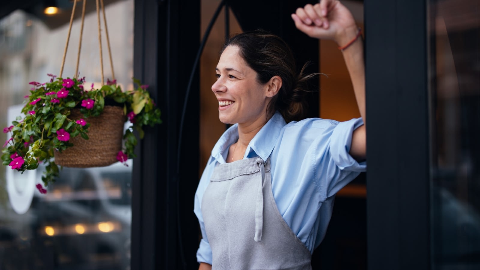 smiling female business owner standing outside of her shop