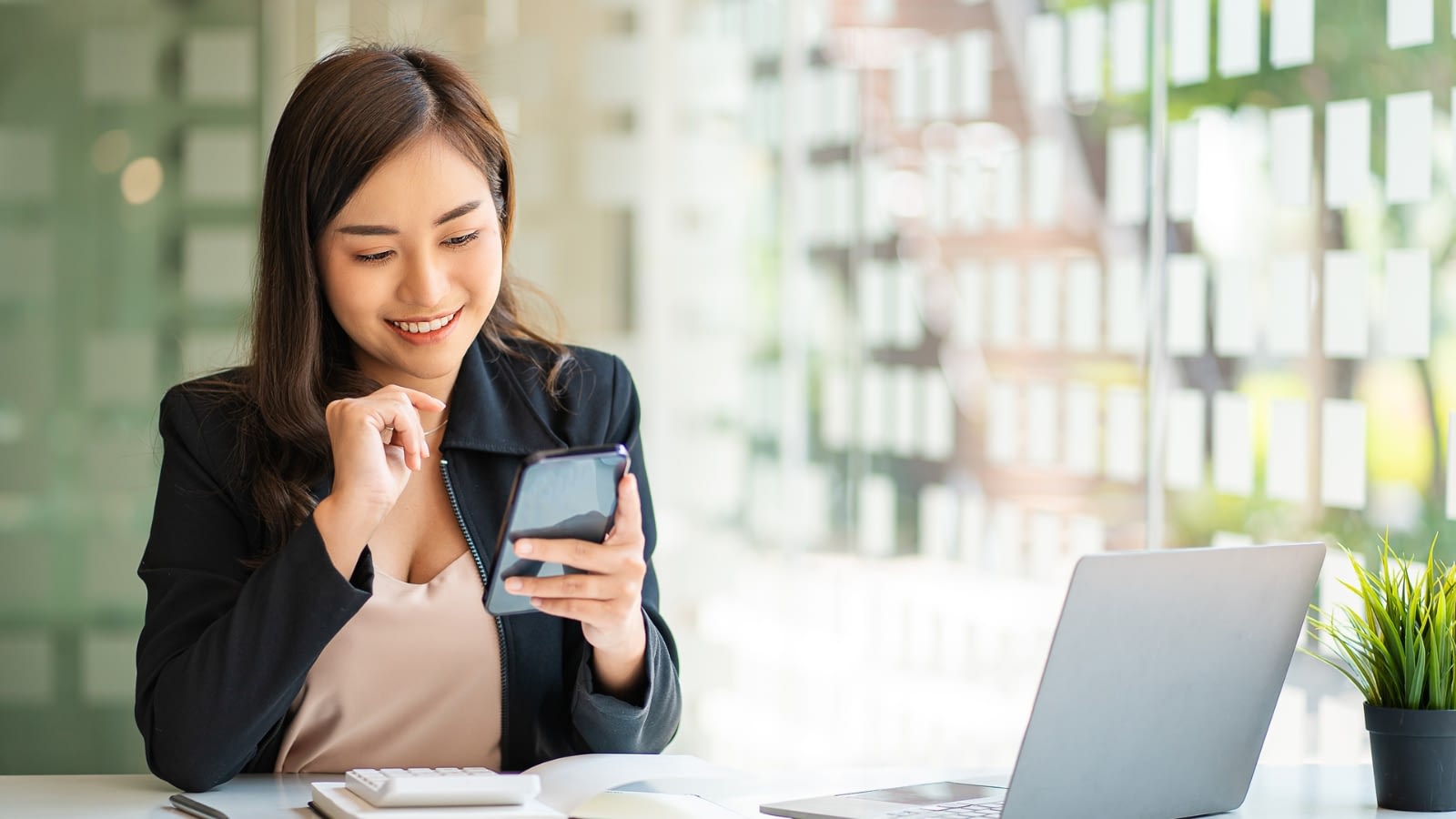 businesswoman smiling while looking at her phone