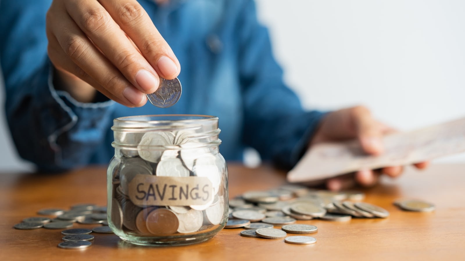 person putting money in savings jar