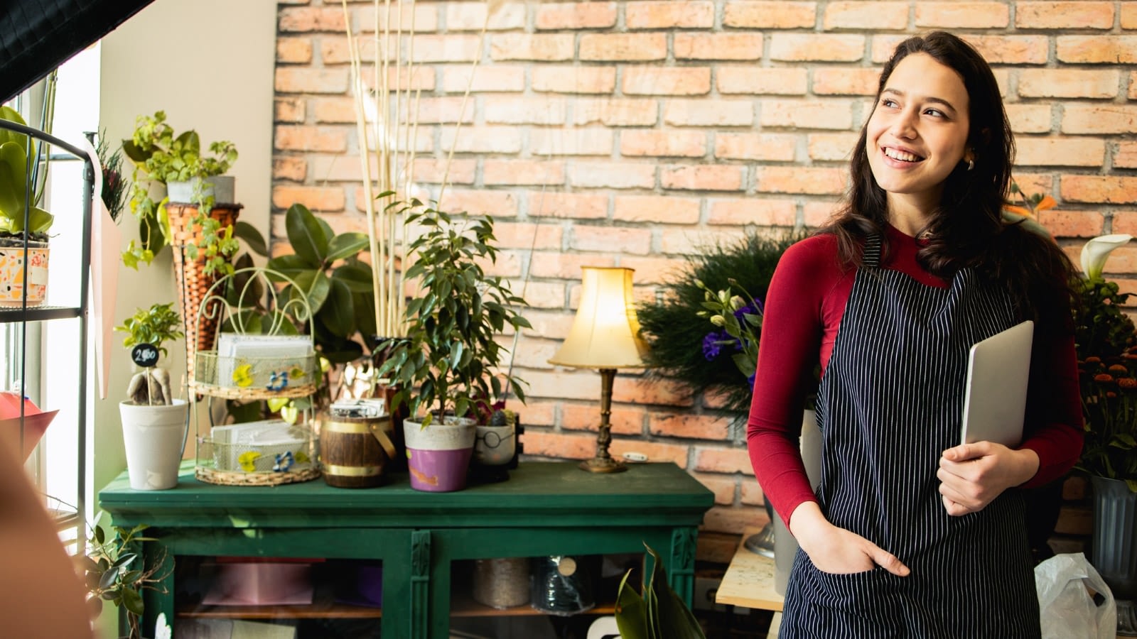 female small business owner holding clipboard deep in thought