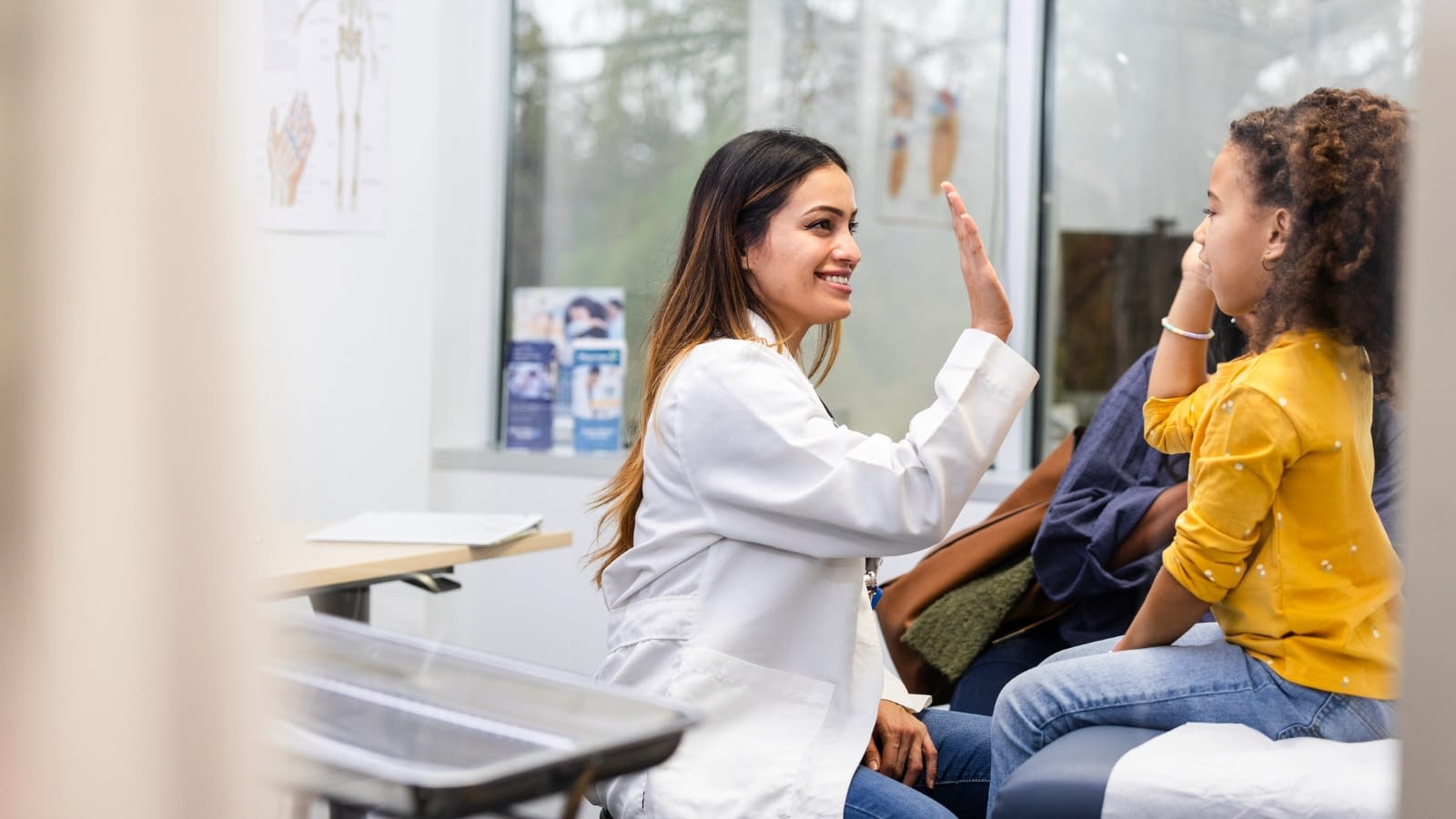 April 25 blog Young female doctor high-fiving child patient.
