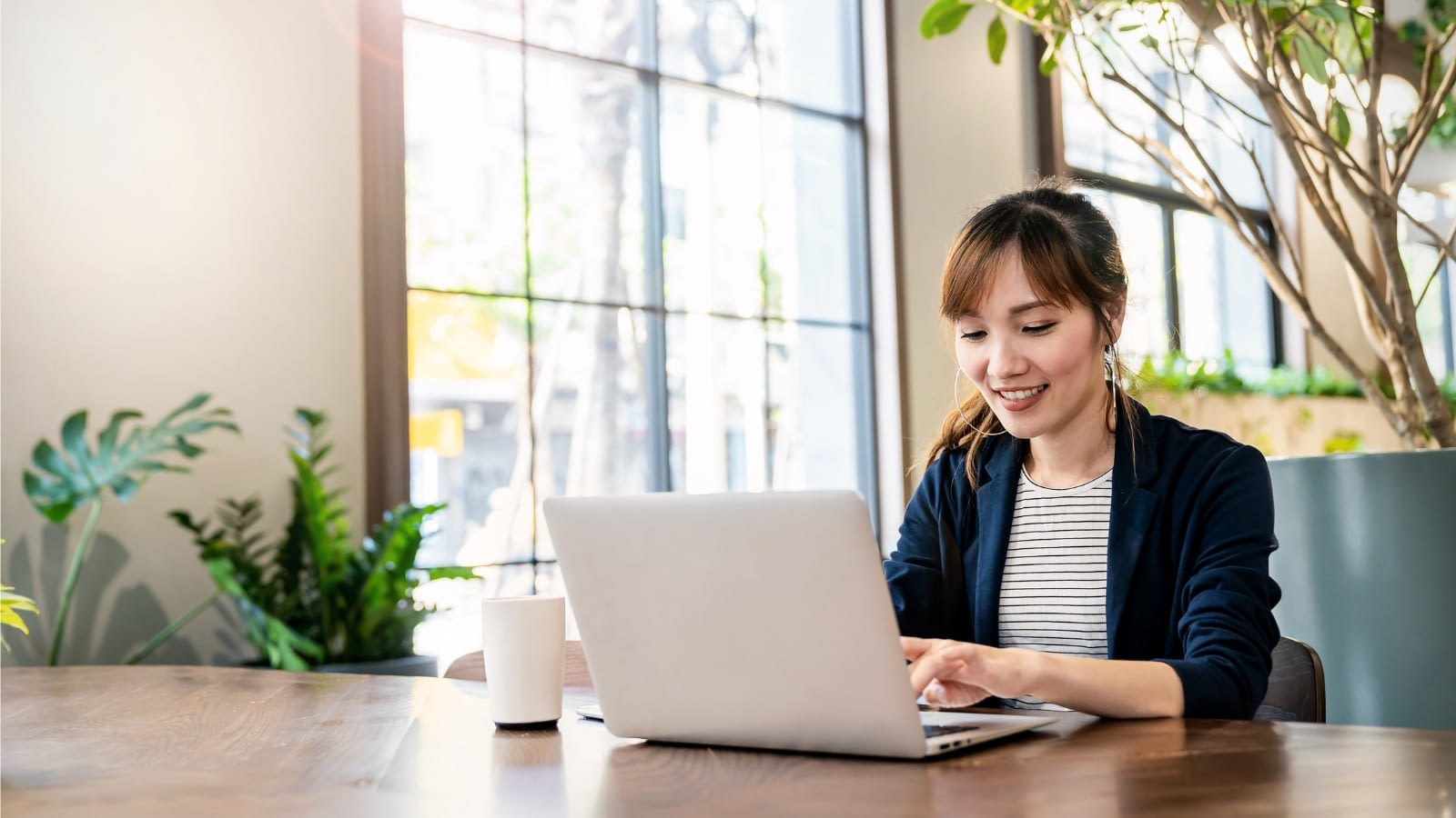 young woman happily working at laptop