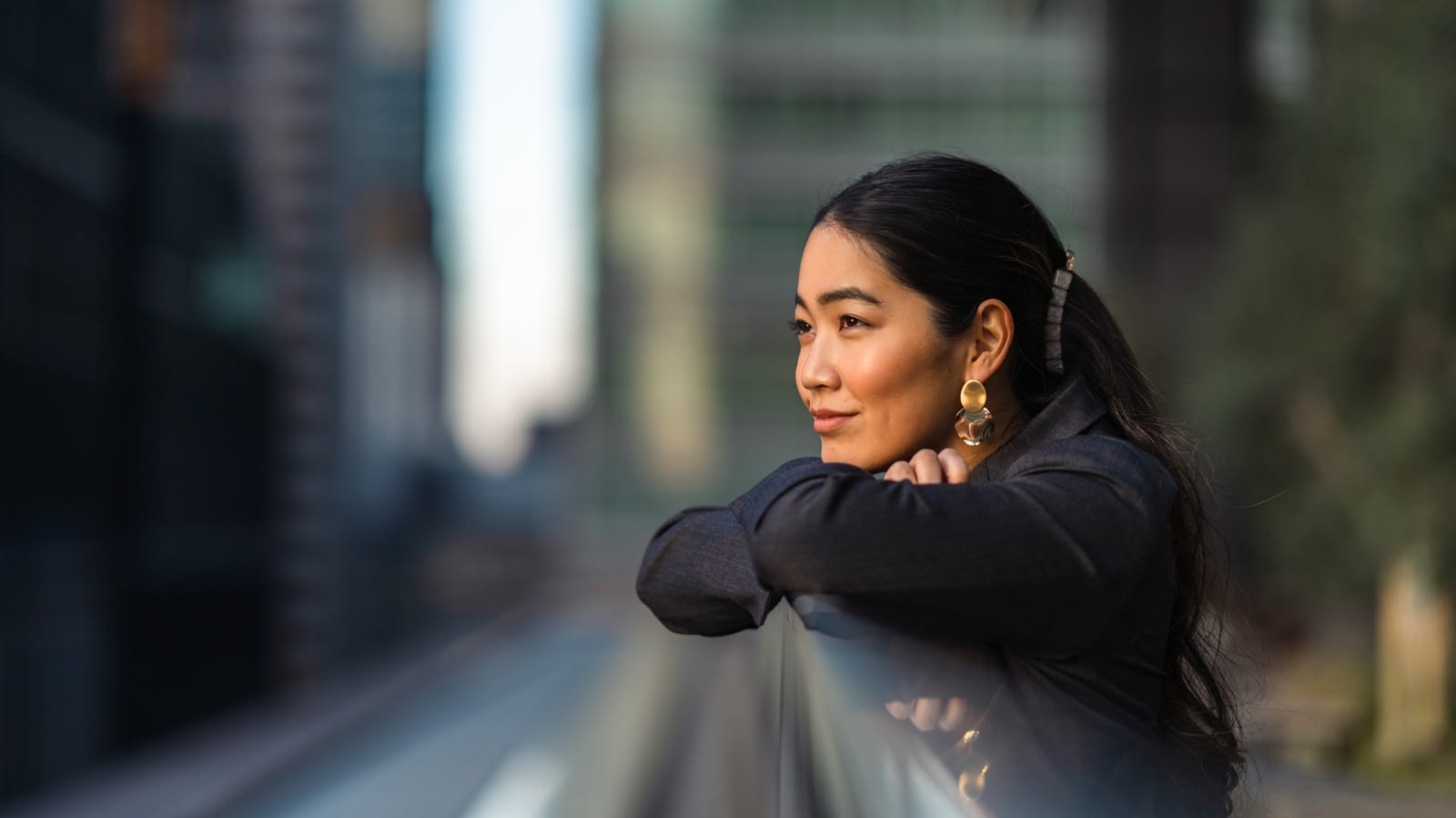 Young Asian woman staring at view off of balcony deep in thought.