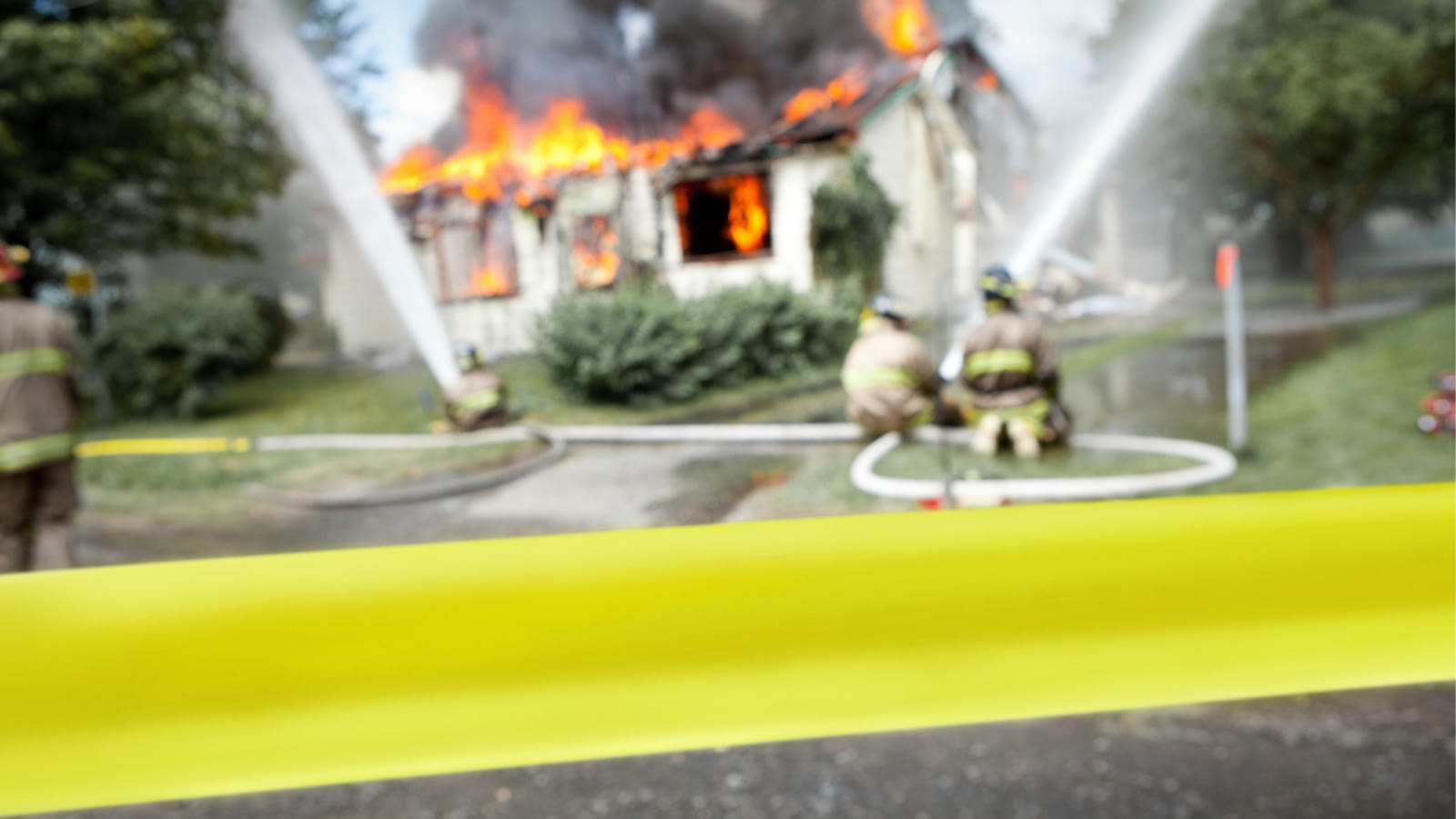 close-up of yellow tape in front of burning house