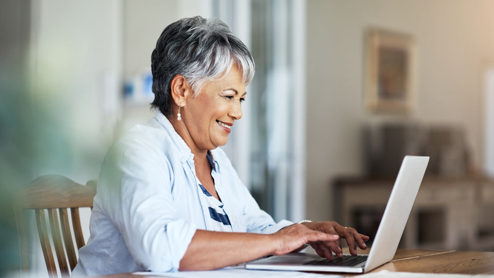 Mar 21 blog Older woman smiling while reading something on her laptop.