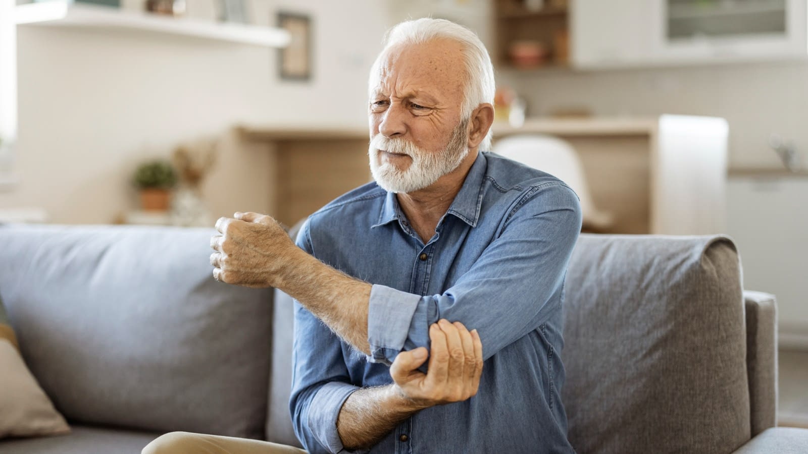 Man in pain holding arm elder man holding elbow
