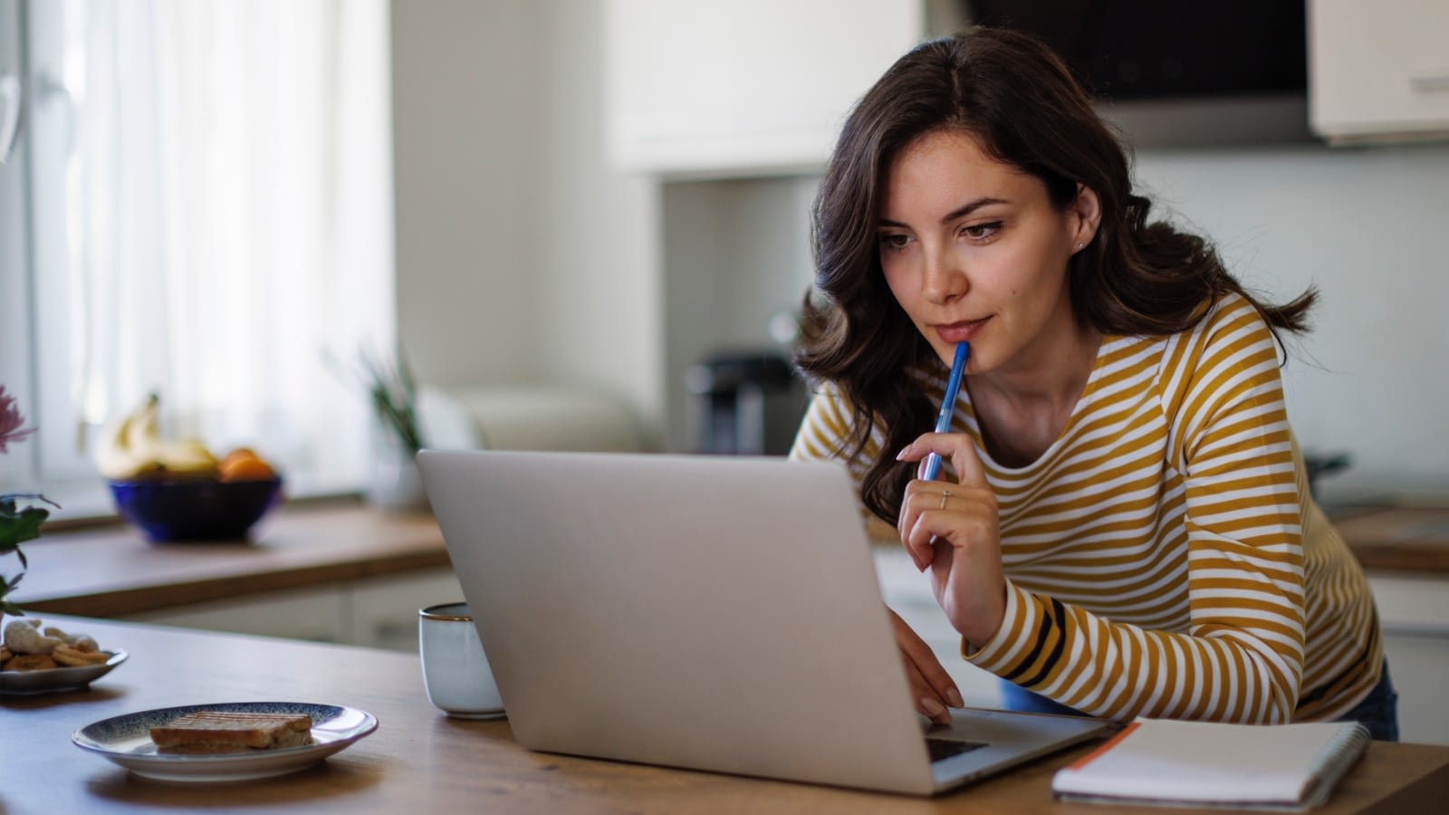 young woman in kitchen researching something online