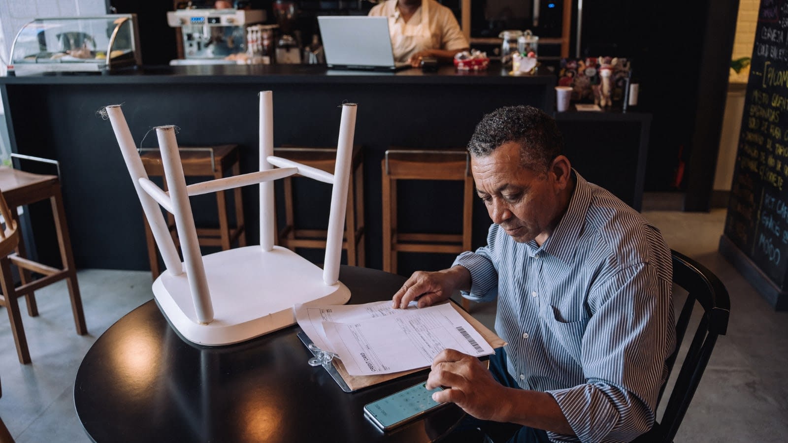 August 4 Restaurant owner sitting at table going over paperwork