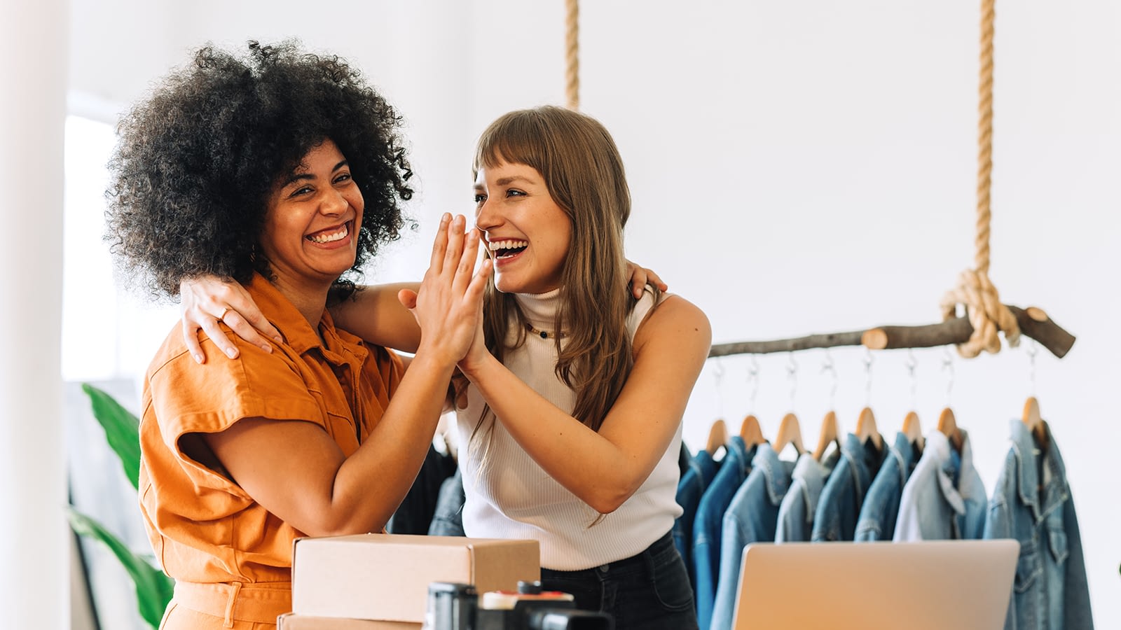 Two women high-fiving in front of apparel