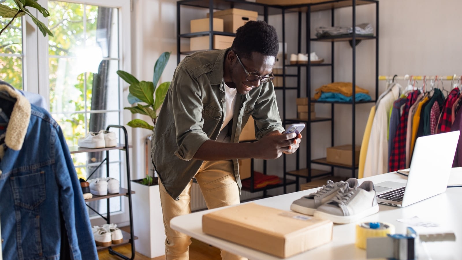 young African-American man taking picture of new inventory for side business