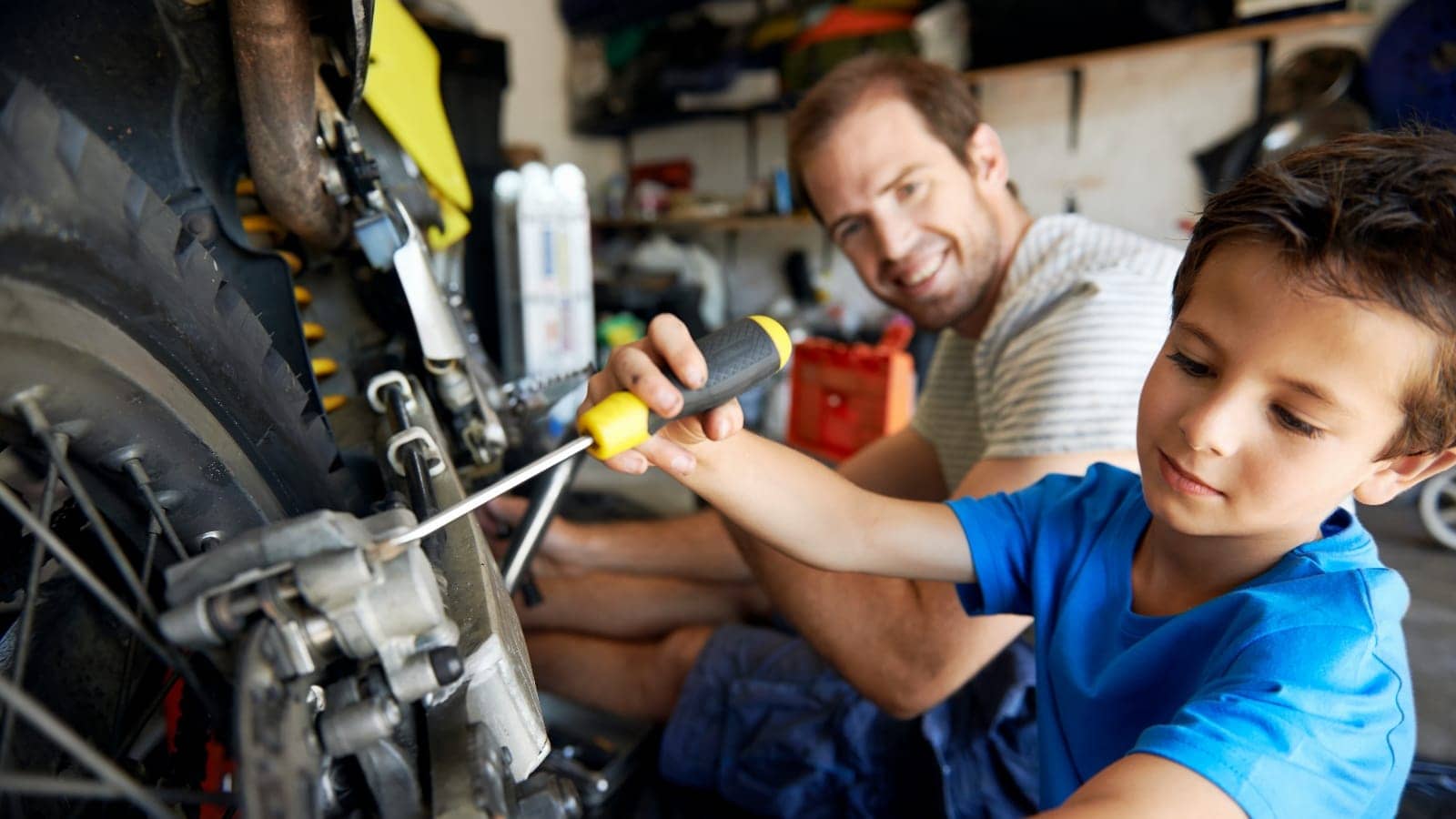 father and young son working on a motorcycle