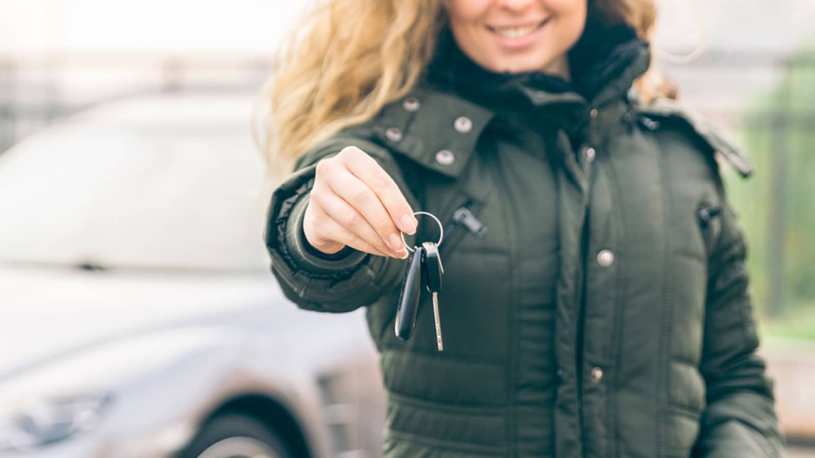 Smiling woman holding out car keys