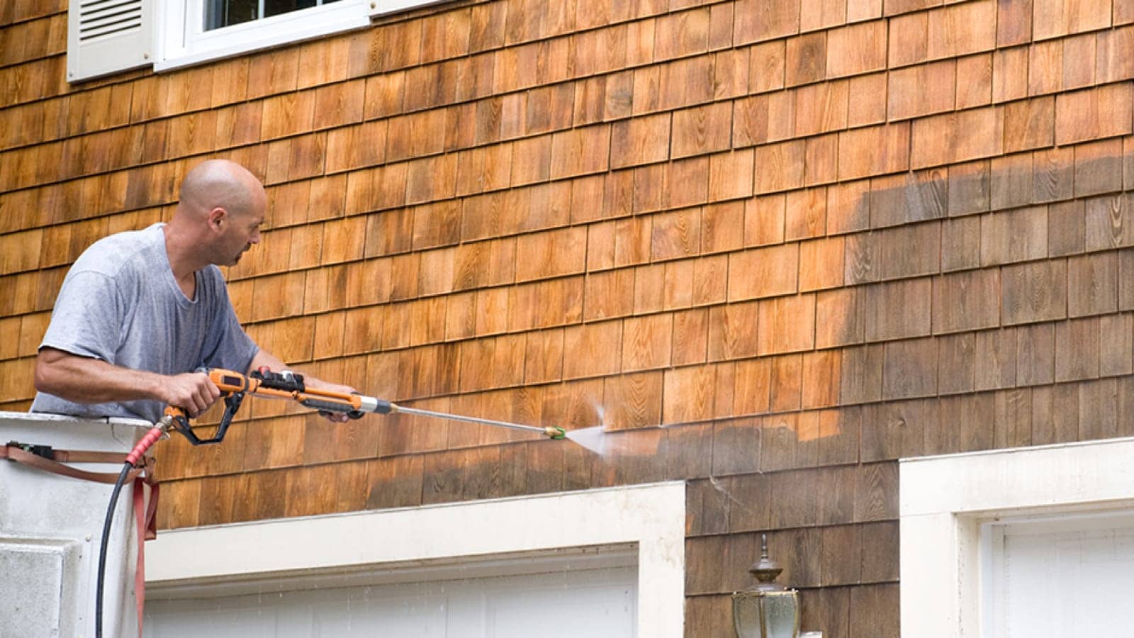 Man pressure-washing the side of a house