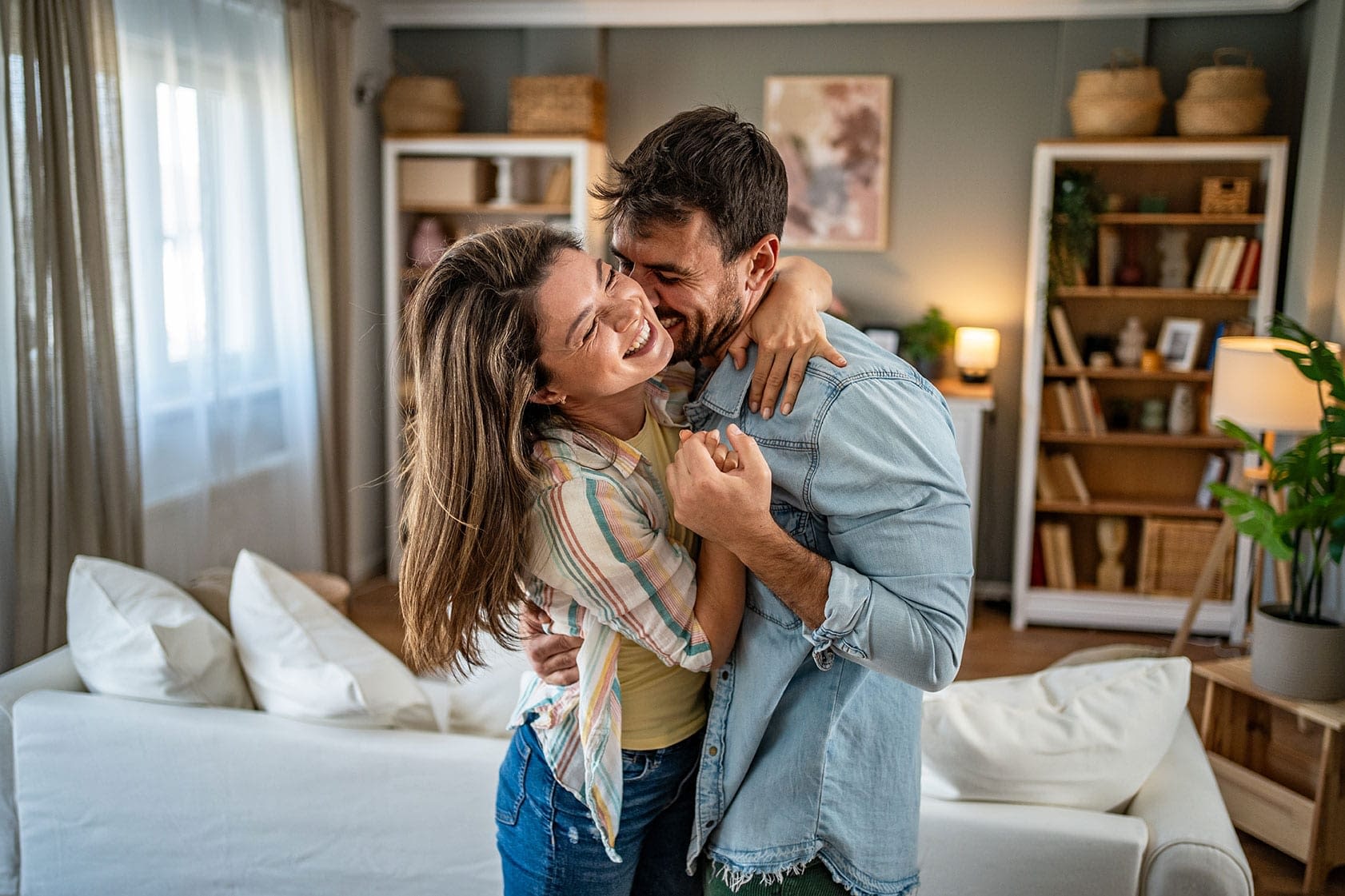 Happy couple embracing and laughing in a living room