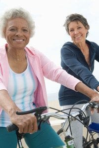 Two Senior Women Riding Bicycles on the Beach