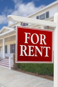 House with a FOR RENT sign in the front yard.