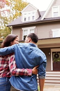A couple hugging while walking towards their house.