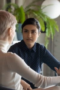 Two females having a conversation at a table.