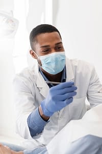 Friendly dentist working on patient's teeth.