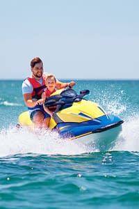A man and his child riding a yellow jet ski on the ocean