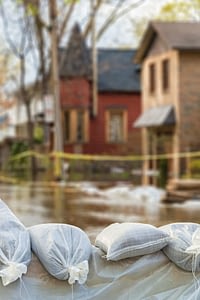Bags of sand sitting on ground in front of two houses