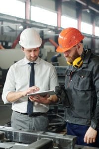 Foreman and worker in conversation at a manufacturing facility.