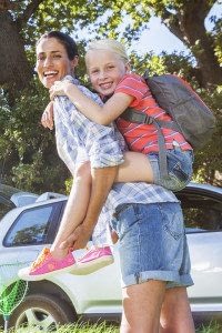 Woman Carrying a Young Girl on Her Back Standing in Front of A White SUV