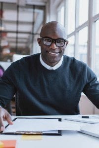 Male Employee Sits in Front of FSA and Other Group Benefits Documents while Smiling at the Camera