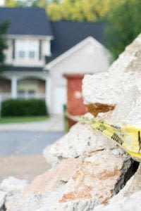 Caution Tape Shown on Rocks in Front of a Residential Neighborhood After an Earthquake