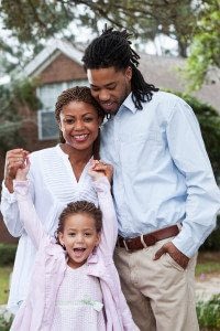 Happy Husband, Wife, and Child Standing in Front of Their New Home