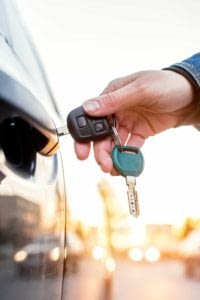 Close up of a person's arm unlocking a car door.