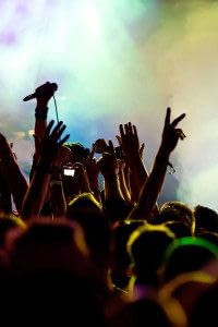 Silhouette of Heads and Hands Raised with Colorful Smoke Above Them at a Concert