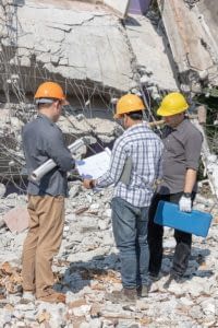 Three construction workers assessing damage to building from earthquake.