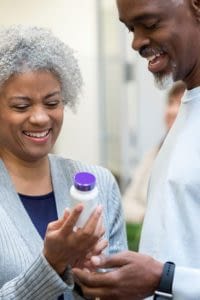 Senior couple reading medicine bottle labels in pharmacy.