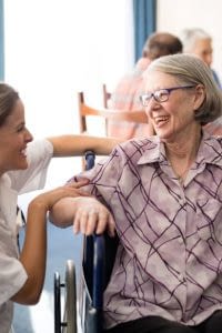 Health care worker providing care to patient in a wheelchair.
