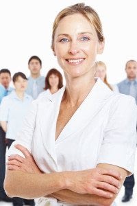 Key Person Female Employee Standing in Front of Team Smiling with Arms Crossed