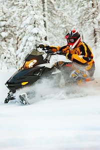 Person riding a snowmobile in snowy landscape.