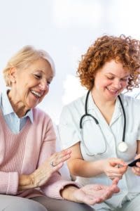 Health care worker measuring a women's blood sugar.