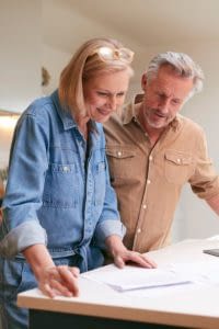 Mature couple reviewing universal life paperwork in their kitchen.