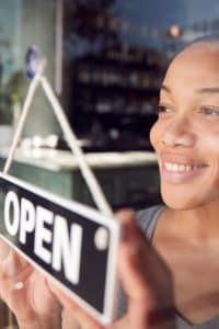 Female Restaurant Business Owner hanging a open sign