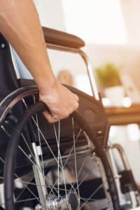 Closeup of the side of a wheelchair and person's arm.