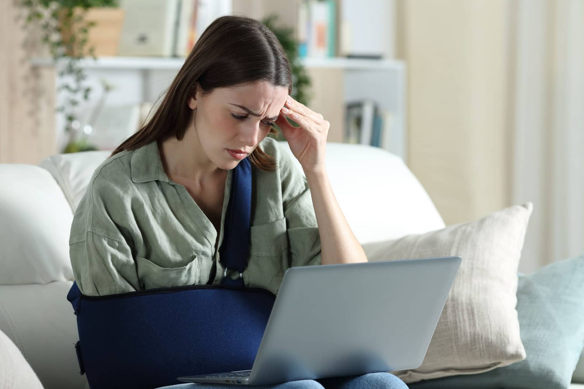 Frustrated Injured Woman Looking at Laptop