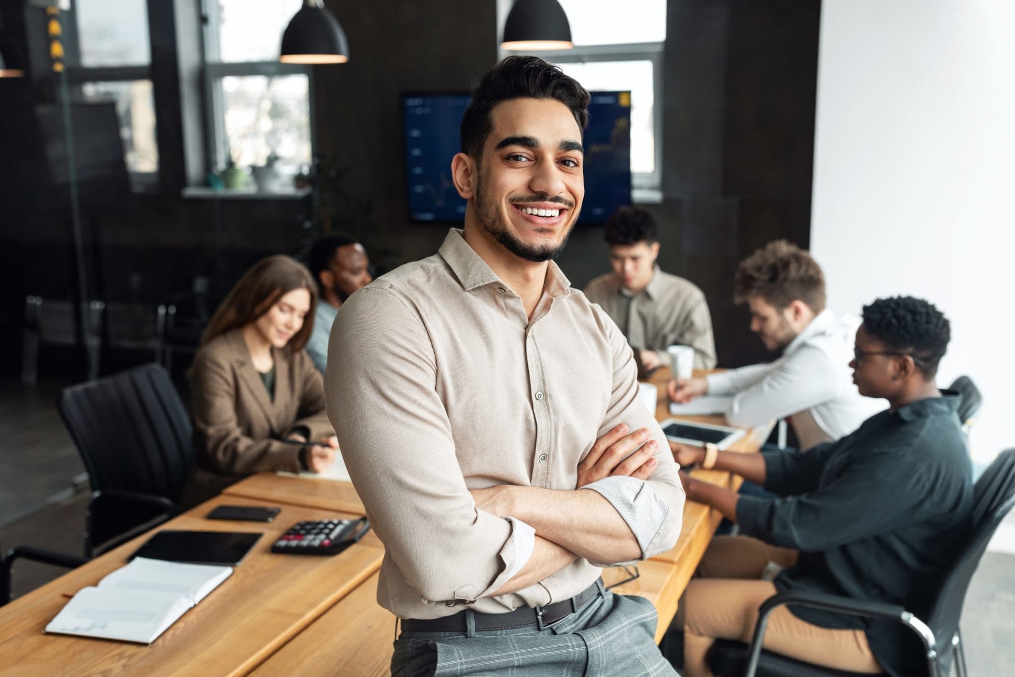 Smiling Young Businessman Sitting on Desk